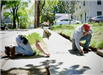 2 workers on Hunt street on knees repairing walkway