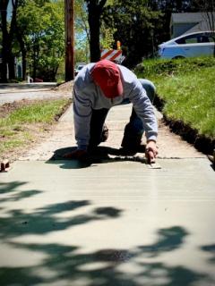 Worker on Hunt street on knees repairing walkway